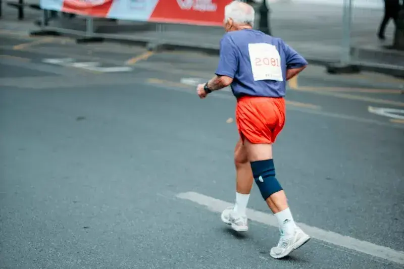 Adulto mayor corriendo con una rodillera de compresión