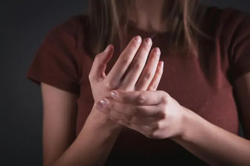 Persona sujetándose la mano por dolor articular